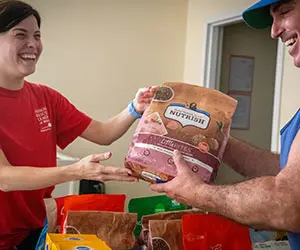 An ARL staff member handing someone a bag of pet food