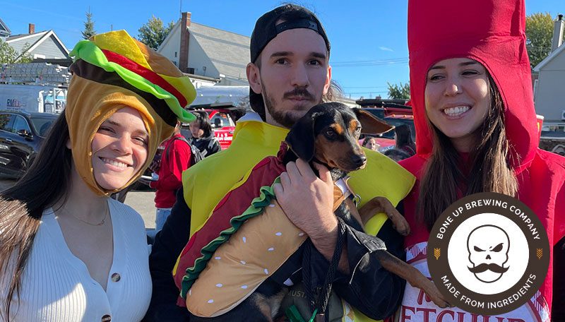 Three people and a dog wearing halloween costumes