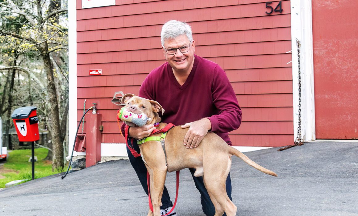 ARL supporter Randy Mason outdoors with a tan pit bull mix dog.