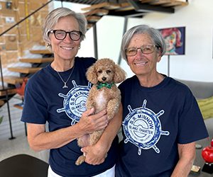 Two people standing next to each other, one person is holding a small dog